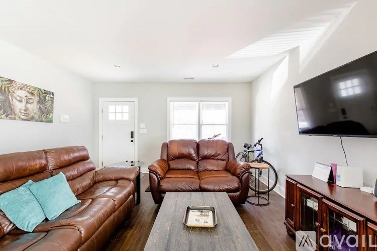 A living room with brown leather furniture and a flat screen TV mounted on the wall.