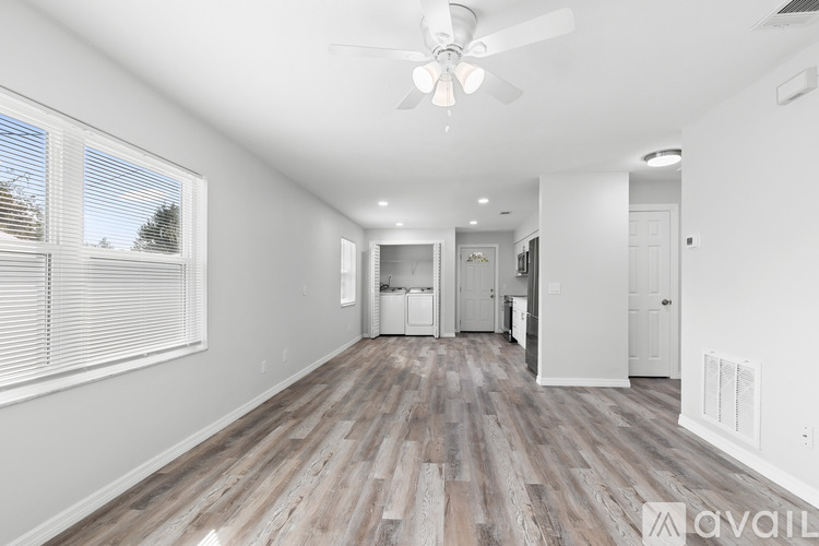 A spacious room with wooden flooring and a ceiling fan.