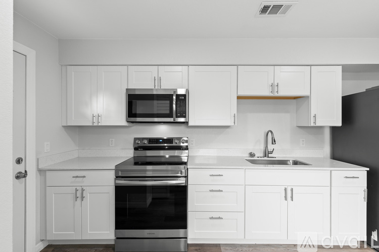 A modern kitchen with white cabinets and stainless steel appliances.