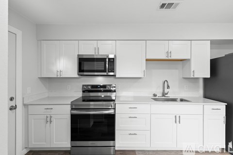 A modern kitchen with white cabinets and stainless steel appliances.
