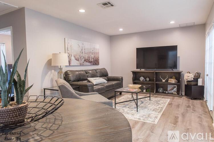 A modern living room with a grey sofa, a wooden coffee table, and a flat screen TV mounted on the wall.