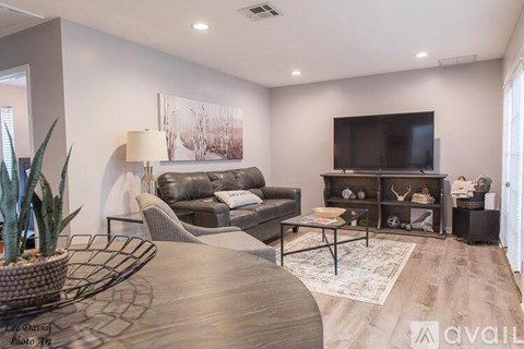 A modern living room with a grey sofa, a wooden coffee table, and a flat screen TV mounted on the wall.