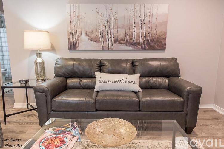 A living room with a grey couch and a painting on the wall.