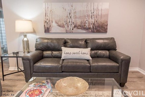 A living room with a grey couch and a painting on the wall.