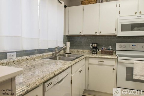 A kitchen with white cabinets and granite countertops.