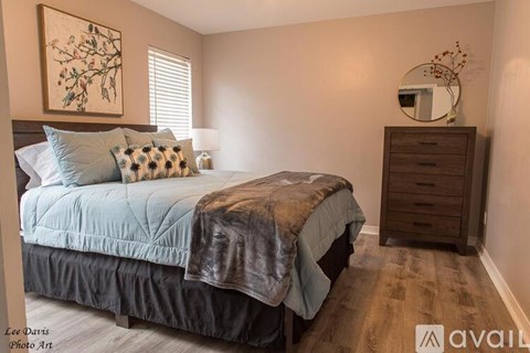 A bedroom with a bed, dresser, and a painting on the wall.
