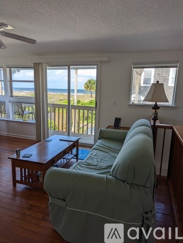 A living room with a couch and a view of the beach.
