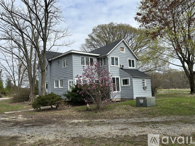 A house with a grey exterior is surrounded by trees and bushes.