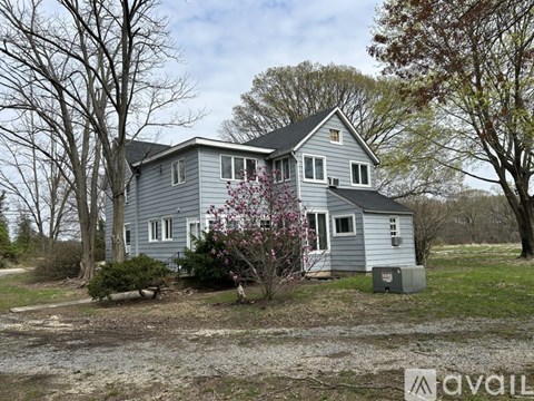 A house with a grey exterior is surrounded by trees and bushes.
