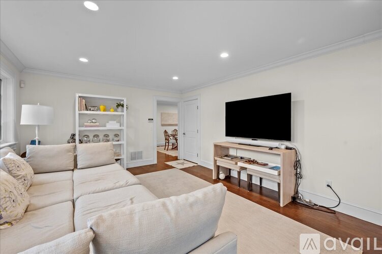 A living room with a white couch and a television on a stand.
