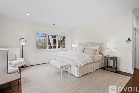 A bedroom with a large bed and a chair.
