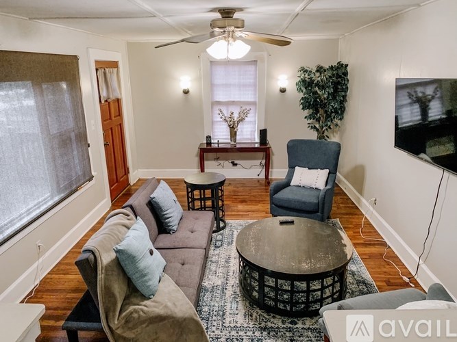 A living room with a brown couch, a blue chair, and a ceiling fan.