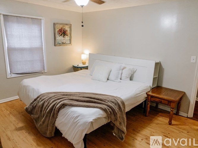 A bedroom with a bed, a small table, and a window.