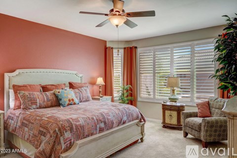 A bedroom with a bed, chair, and potted plant.