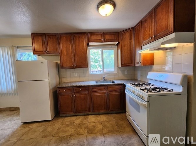 A kitchen with a white refrigerator, a white stove, and wooden cabinets.