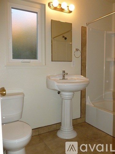 A bathroom with a toilet, sink, mirror and tub.