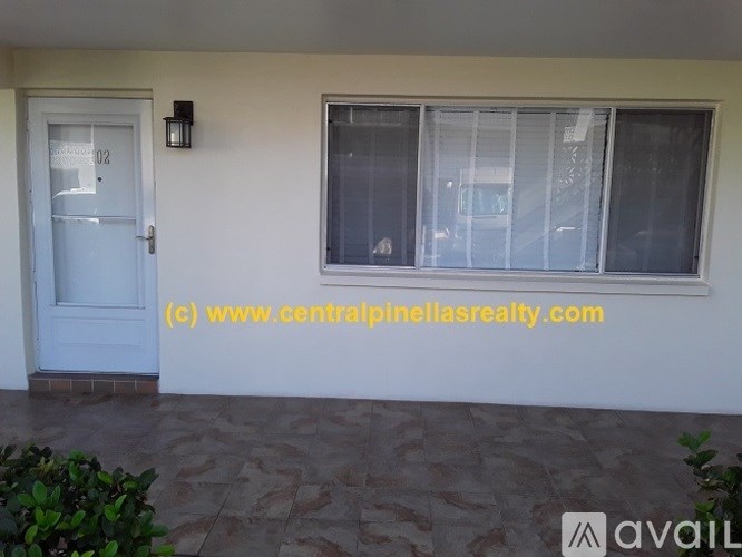 A white door with the number 102 on it is on the left side of a window with a white curtain.