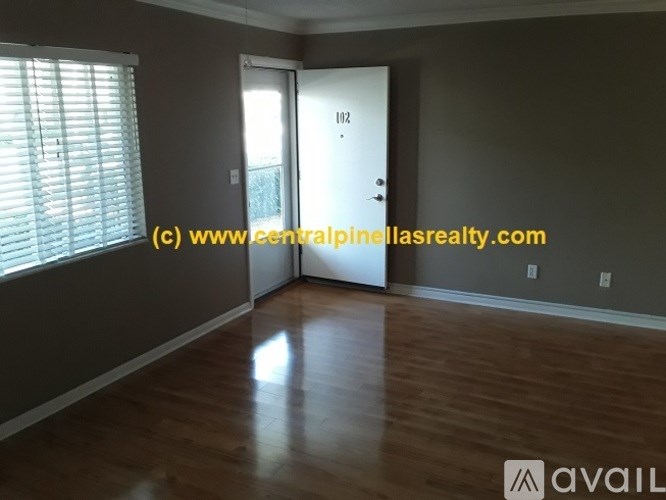 A room with wooden flooring and a door leading to another room.