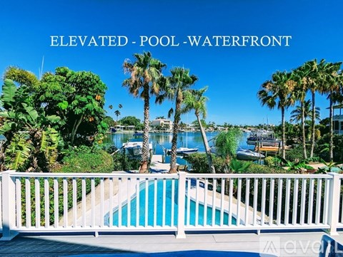 A pool surrounded by palm trees and bushes.