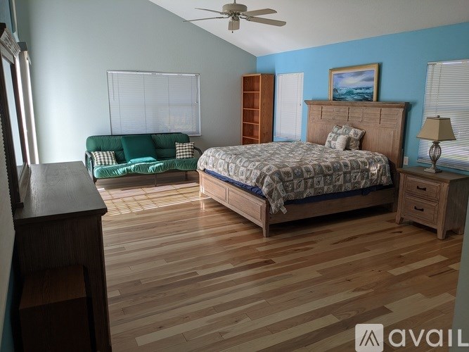 A bedroom with a bed, dresser, and a green couch.