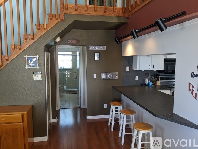 A kitchen with a bar stool and a staircase.