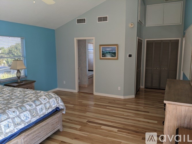 A bedroom with a bed, dresser, and a painting on the wall.