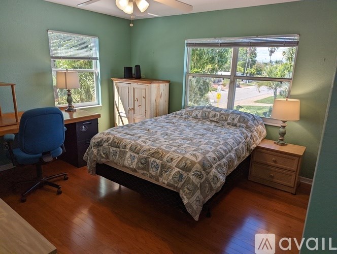 A bedroom with a bed, desk, chair, and window.