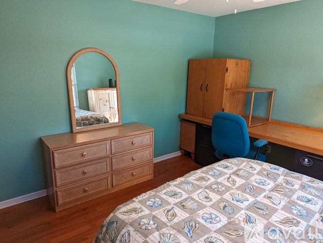 A bedroom with a bed, dresser, and desk.