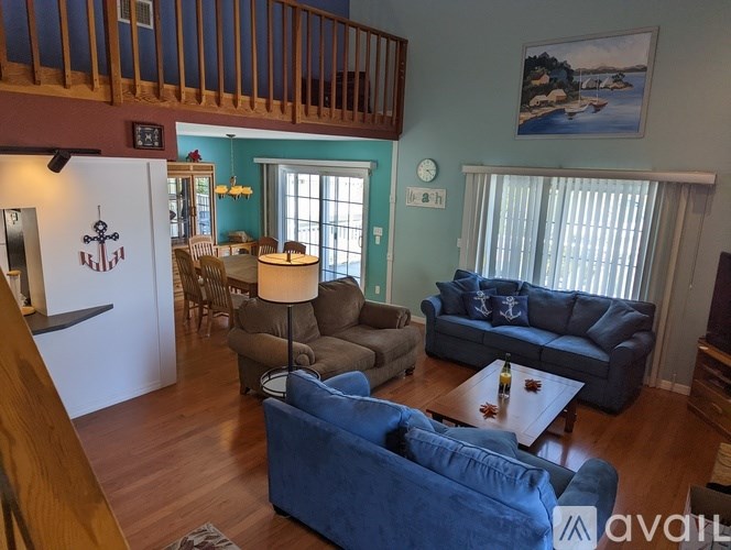 A living room with a couch, chairs, and a painting on the wall.