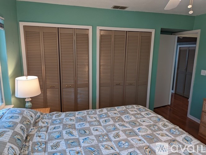 A bedroom with a bed, a lamp, and a window with blinds.