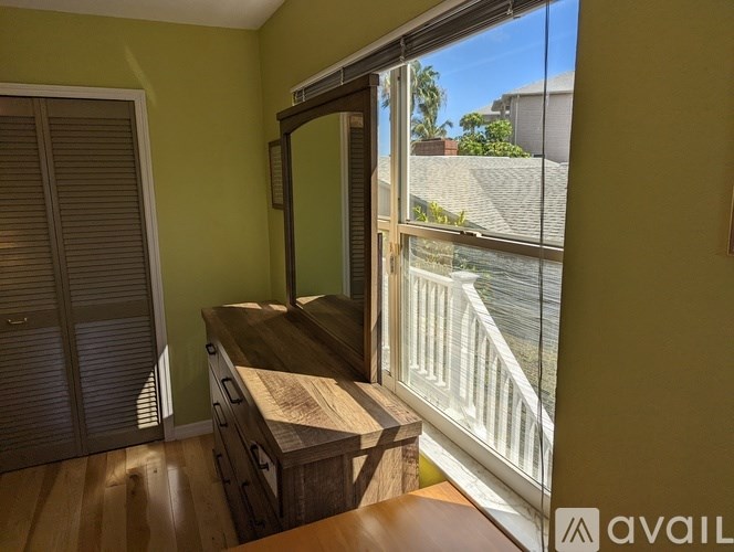 A room with a wooden table and a sliding glass door leading to a balcony.