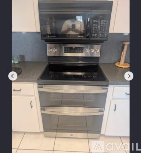 A modern kitchen with a black microwave above a stainless steel oven.