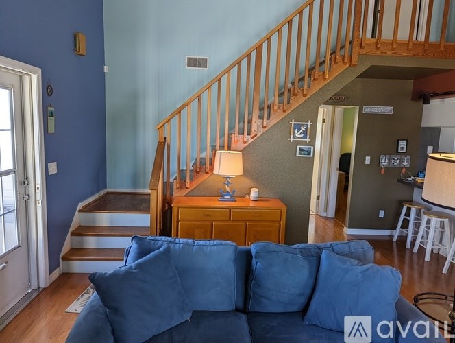A living room with a blue couch and a staircase.