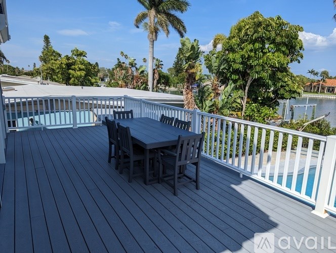 A wooden deck with a table and chairs overlooking a pool.