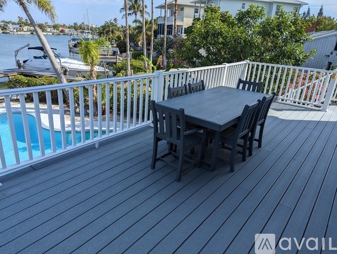 A table and chairs set on a wooden deck overlooking a body of water.