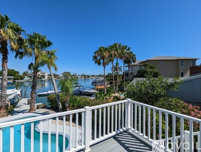 A white deck with a pool and palm trees.
