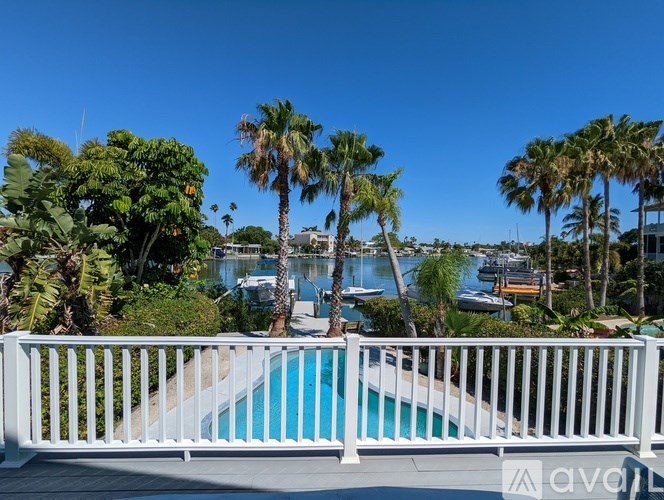 A pool surrounded by palm trees and a white fence.