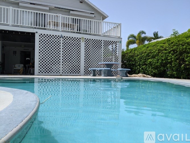 A pool in front of a house with a white lattice screen.