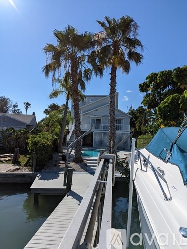 A white boat is docked at a wooden pier.