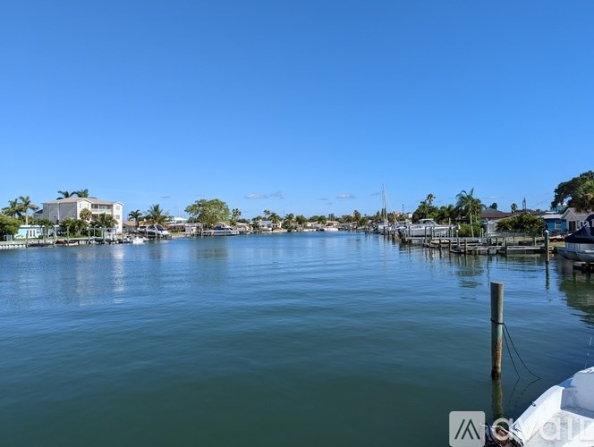 A calm body of water with a dock and buildings in the distance.