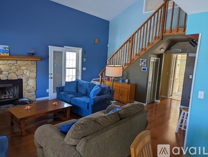 A living room with a stone fireplace and blue walls.