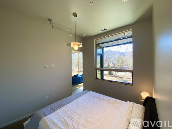 A bedroom with a large bed and a window overlooking a tree-filled landscape.
