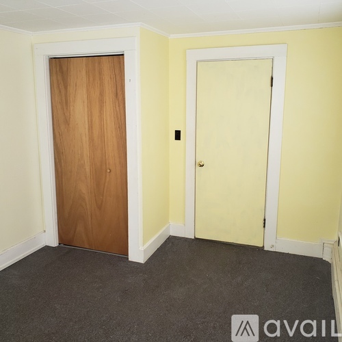 A room with a wooden door and a white door.
