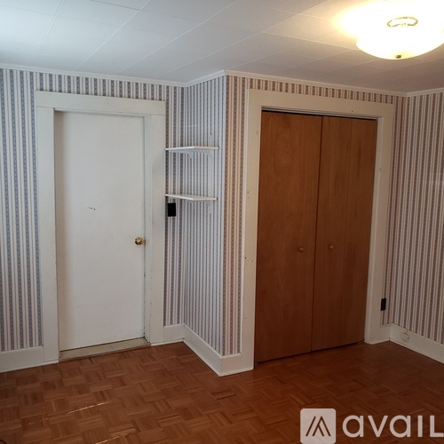 A room with striped wallpaper and a wooden door.
