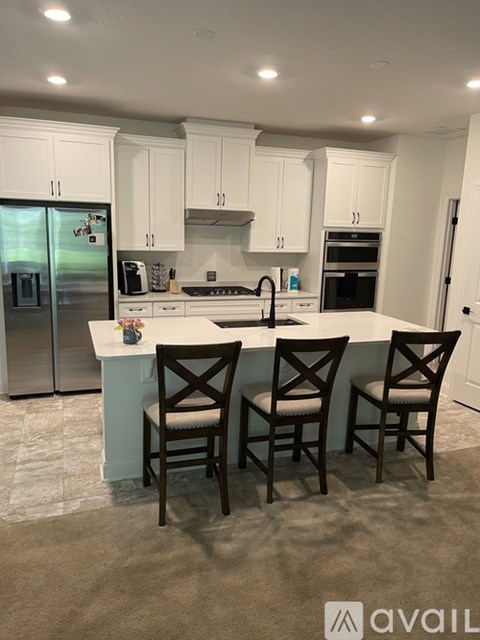 A kitchen with white cabinets and a center island with two chairs.