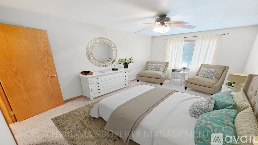 A bedroom with a large bed, two chairs, and a mirror on the wall.