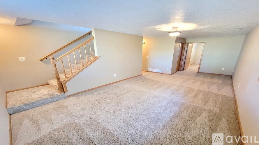 A spacious room with a carpeted floor and a staircase leading to the upper level.