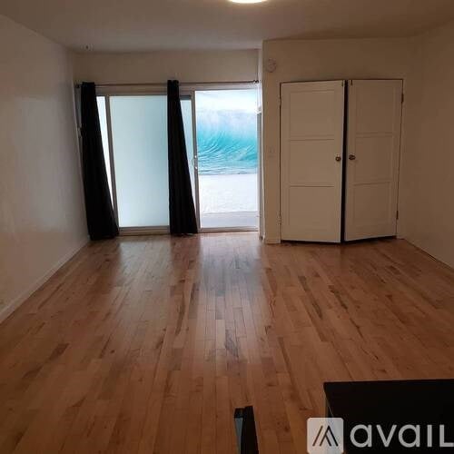 A room with wooden floors and a view of the beach through the window.
