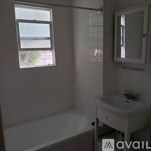 A white bathroom with a tub, sink, and mirror.