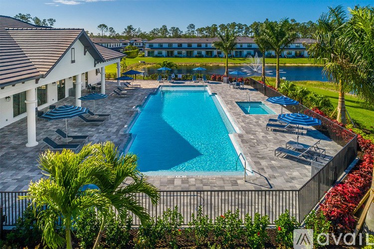 A large outdoor swimming pool surrounded by palm trees and a white building.